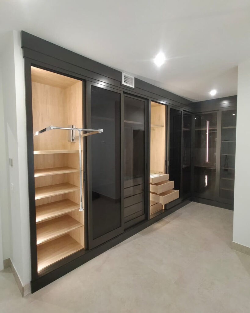 Elegancia y funcionalidad: un vestidor con puertas de cristal ahumado e iluminación interior